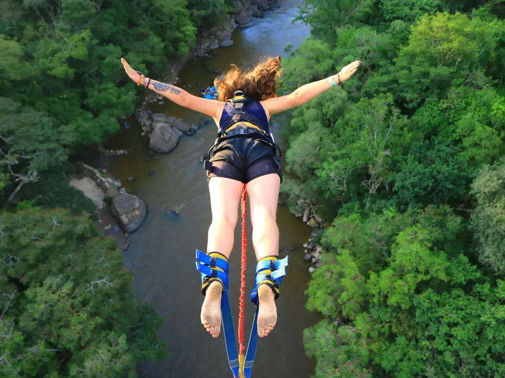 Salto de bungee jumping sobre el río, con los brazos abiertos