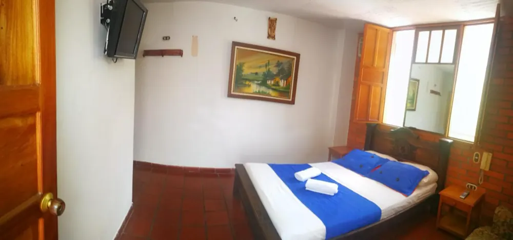 Habitación doble con televisor y un cuadro en la pared
