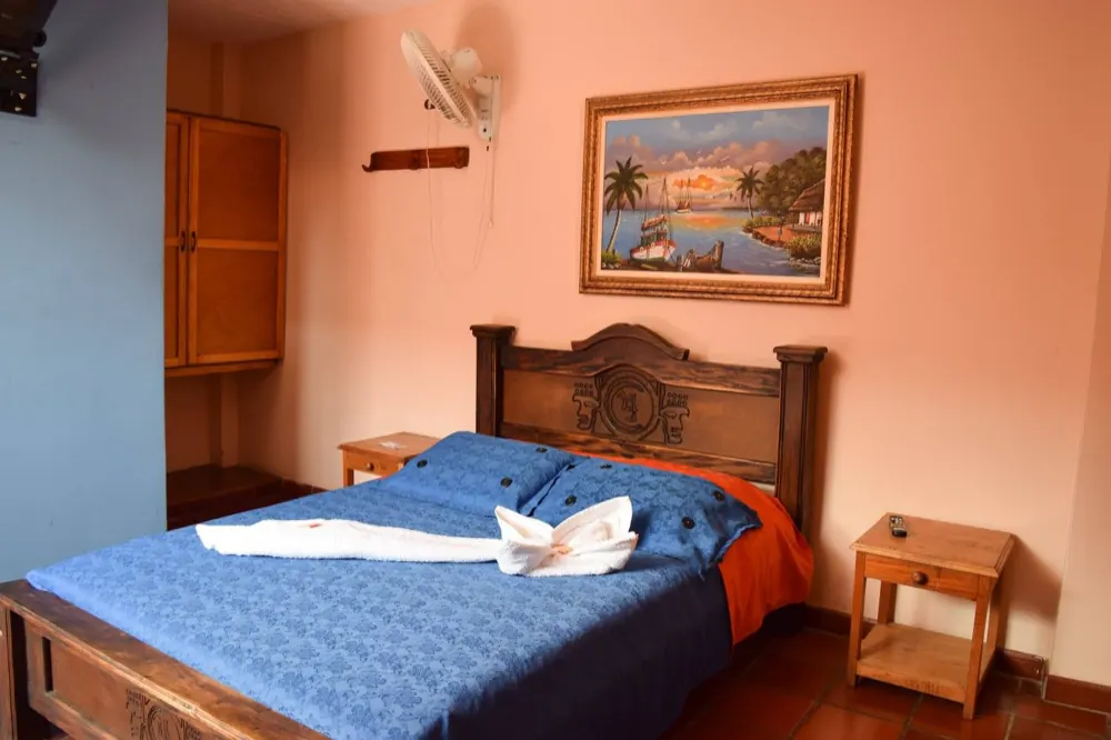 Suite con cama doble, cuadro y muebles en madera