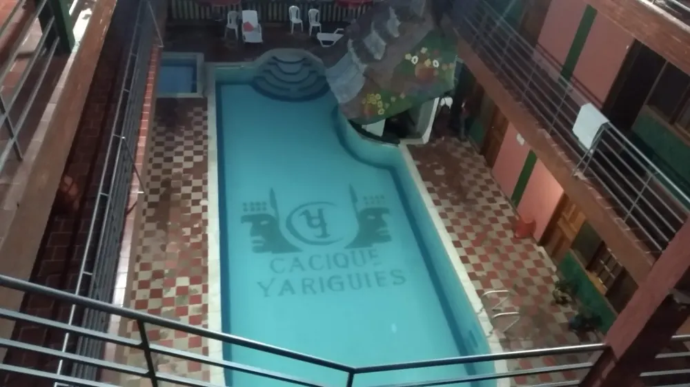 Piscina con el escudo del hotel en el fondo, vista desde el corredor